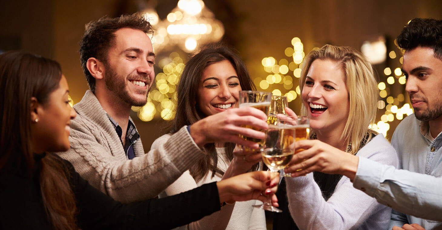 Smiling man and women sitting in bar toasting with beer glasses