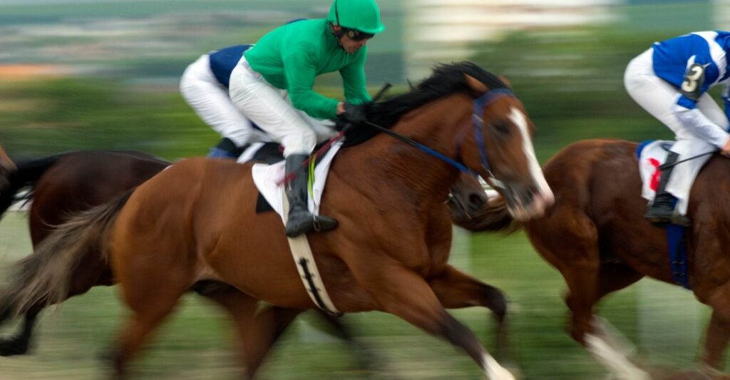 Blurred image of three horses and their jockeys racing