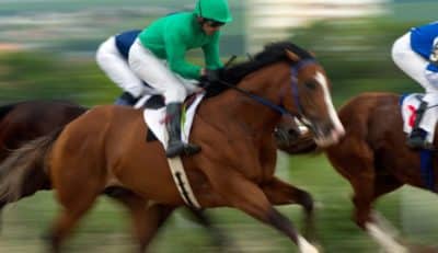 Blurred image of three horses and their jockeys racing