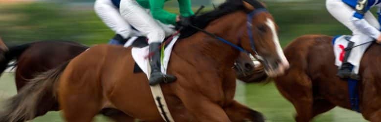 Blurred image of three horses and their jockeys racing