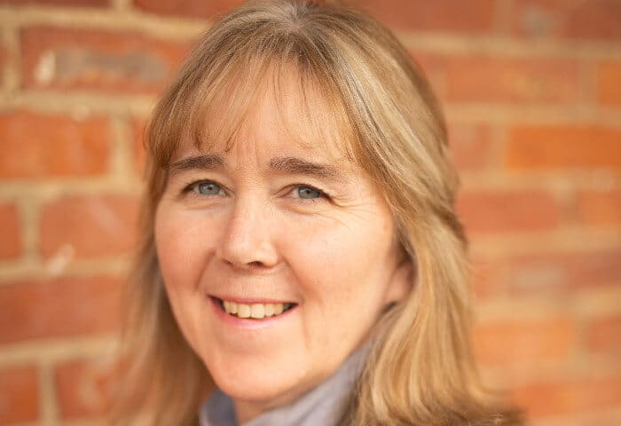 Headshot of smiling housekeeping supervisor Kim by red brick building