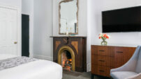 King Room with fireplace with framed mirror handling above mantel, flat screen tv hanging on wall above dresser