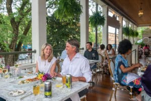 Group of guests sitting at tables in evening gathered for dinner on covered porch at Saratoga arms